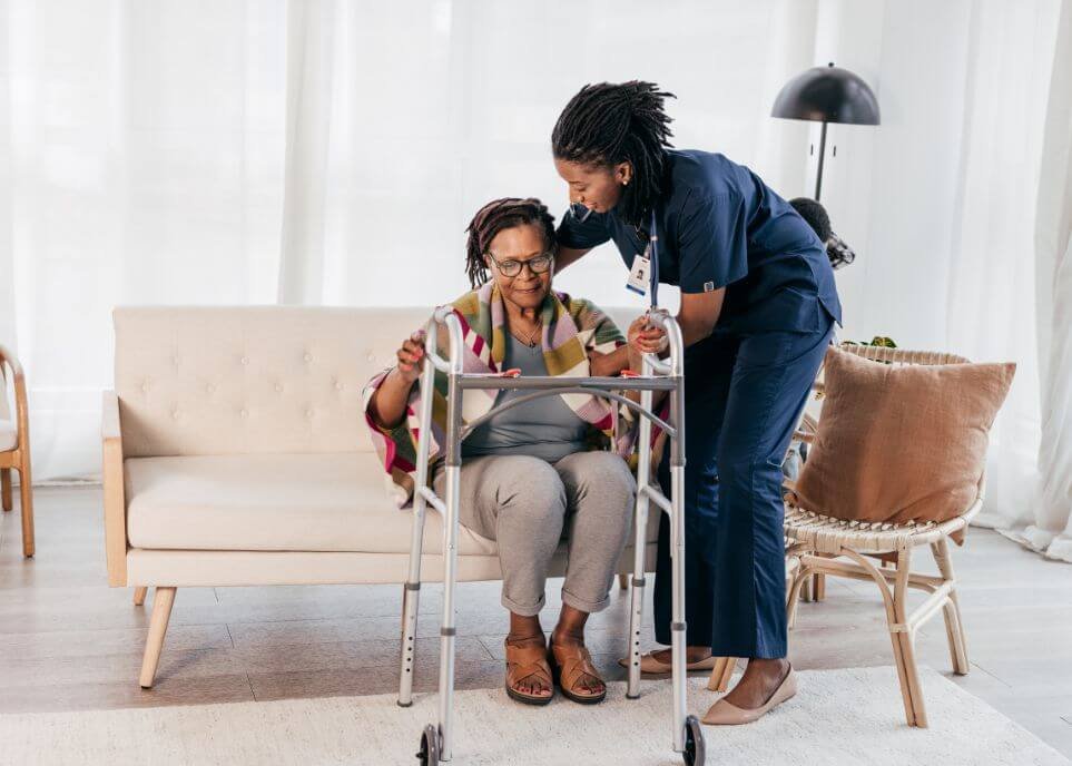 nursing assistant helping elderly stand to walker
