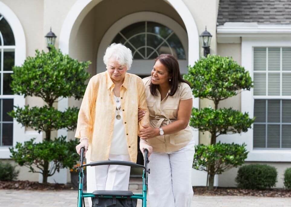daughter helping elderly mother with walker