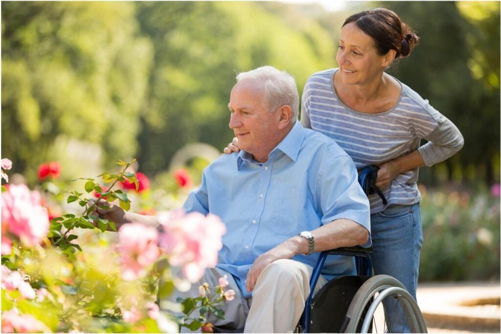 daughter pushing father in wheelchair in flower garden