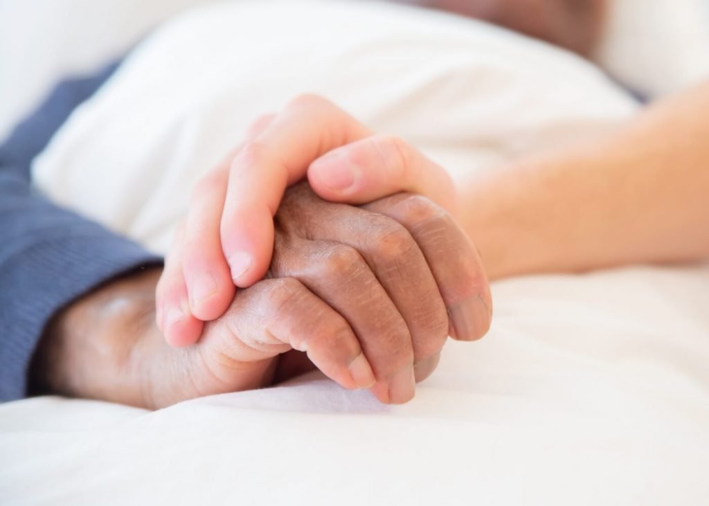 holding elderly's hands during hospice care
